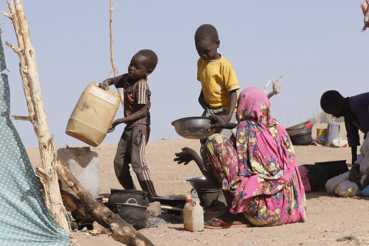 Unos niños ayudan a preparar comida en un campo de desplazados de Sudán.