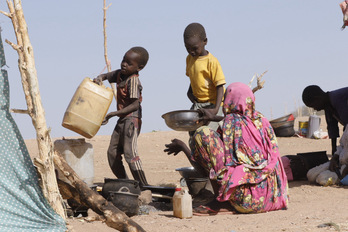 Unos niños ayudan a preparar comida en un campo de desplazados de Sudán.