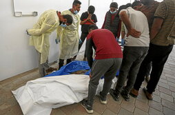 Trabajadores de la morgue del hosital Nasser observan uno de los cuerpo de palestinos entregado.
