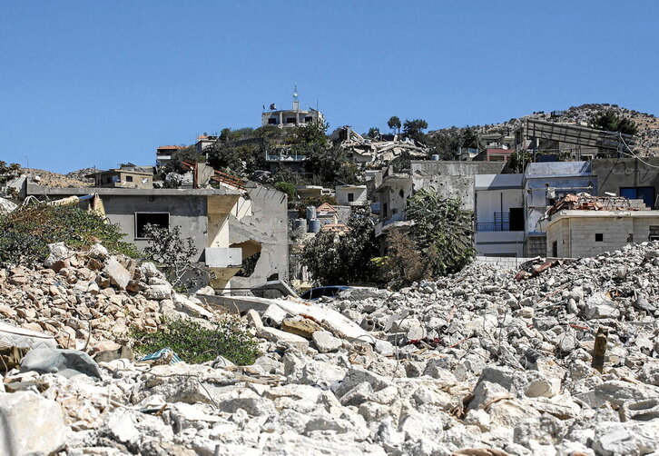 Kfarchouba (arriba), gravemente dañada por los ataques israelíes. Karam Abdoul Fateh (derecha), junto a la casa prefabricada levantada sobre las ruinas de su vivienda.