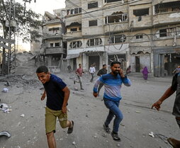 La gente corre a refugiarse tras un ataque israelí contra un edificio en el campamento de Bureij, en el centro de la Franja de Gaza.