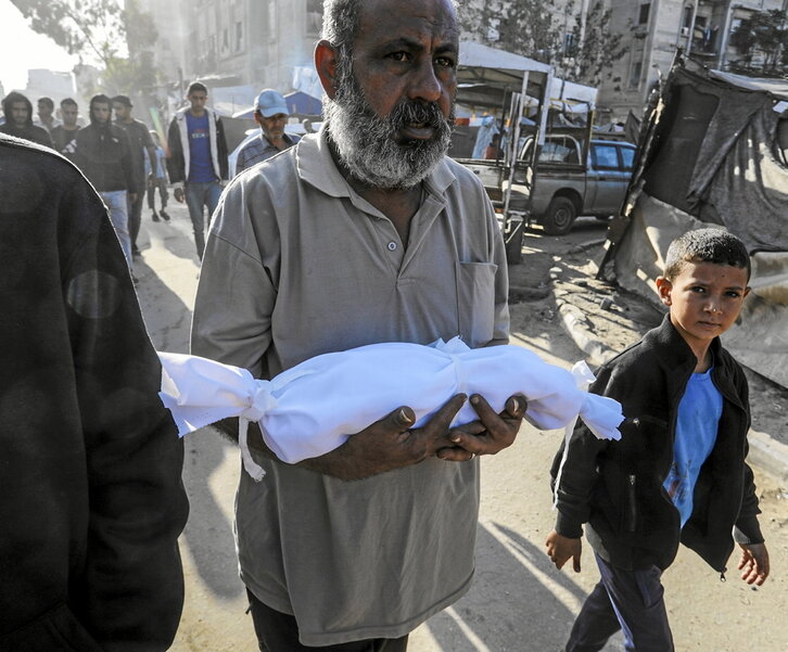 Un hombre lleva un niño muerto en un ataque israelí en Ciudad de Gaza.
