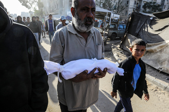 Un hombre lleva un niño muerto en un ataque israelí en Ciudad de Gaza.