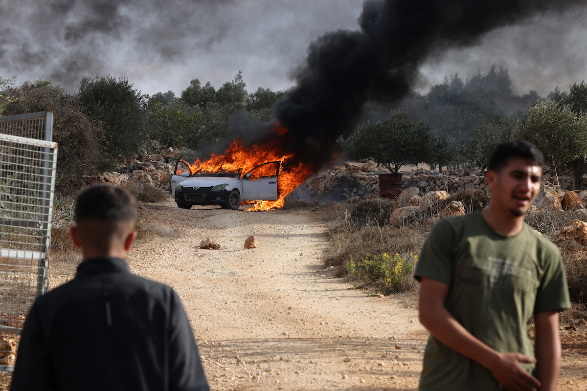 Un coche incendiado por colonos en el ataque durante la cosecha de aceitunas en Turmusaya. (Hazem BADER/AFP)