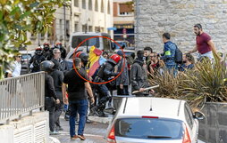 A la persona de azul claro del círculo primero le empuja y amenaza el de la bandera y después le aporrea un ertzaina.