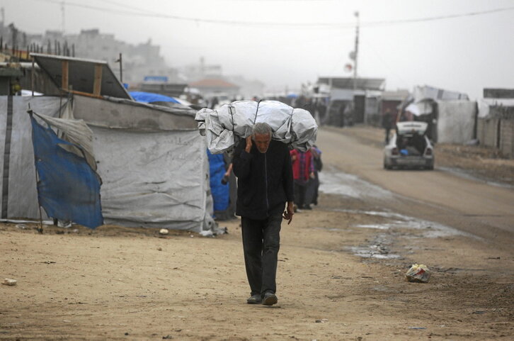 Un palestino desplazado lleva sus pertenencias al oeste de la ciudad de Deir al-Balah, azotada por las lluvias.