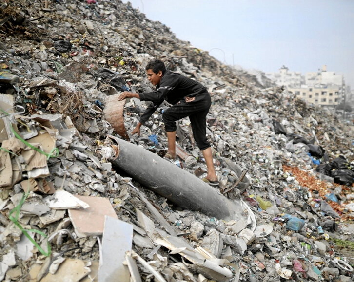 Un niño busca en la basura cerca de un misil.