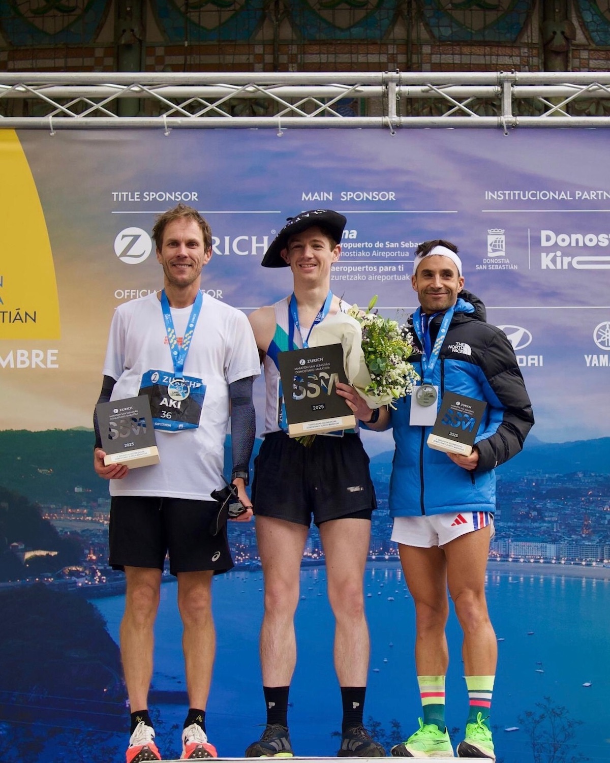 Podio masculino, con el inglés Thomas Holliday en el centro con la txapela de ganador. (ZURICH MARATÓN DE DONOSTIA)