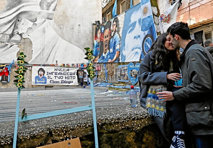 Una pareja se besa en la mítica Via Emanuele de Deo de Nápoles, donde cientos de seguidores dejan allí bufandas del equipo italiano de la ciudad o camisetas de Argentina en honor a Maradona.