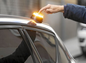 Una persona activa una baliza V-16 colocada en el techo de su coche.
