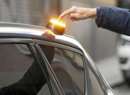 Una persona activa una baliza V-16 colocada en el techo de su coche.