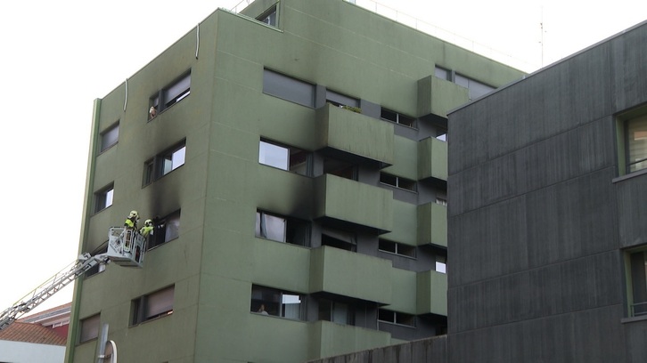 Los bomberos intentan acceder a uno de los pisos altos en la mañana del incendio.