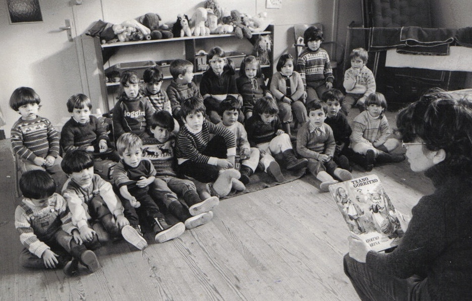 Ikastolako ikasleak 1983an ikasgelan, irakaslea 'Txano gorritxo' irakurtzen ari zaiela. Ikastolako ikasleak 1983an ikasgelan, irakaslea 'Txano gorritxo' irakurtzen ari zaiela.