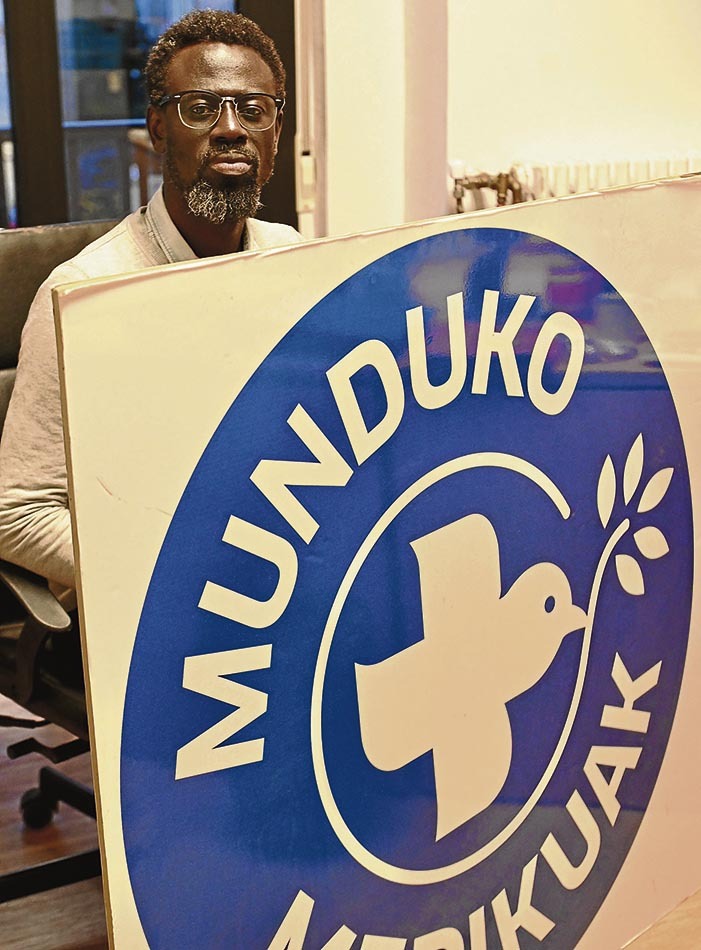 Mamadou Ngom, miembro de la Escuela de Empoderamiento Antirracista de la capital vizcaina, posa con un cartel de Munduko Medikuak. Mikel Martinez de Trespuentes | FOKU