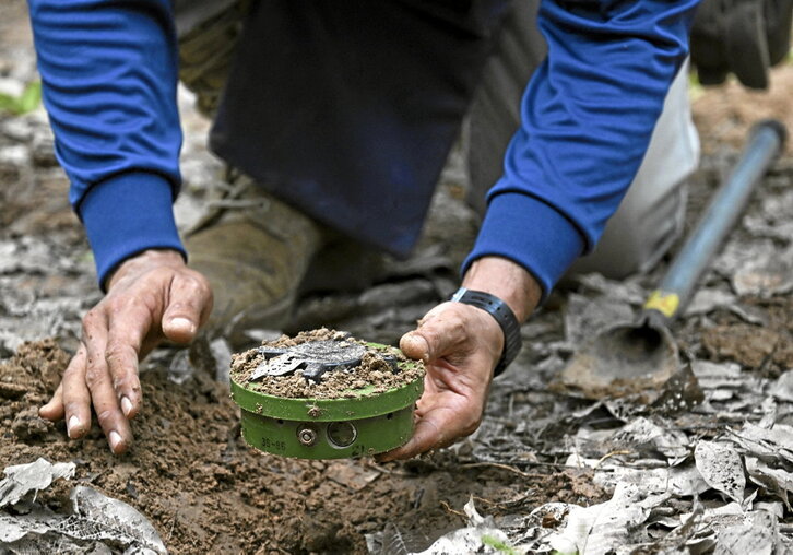 Behean, ezkerretik eskuinera, langileak Thailandiako mugako minak kentzen eta Halo Trust enpresako langileak Mykolaiv eskualdeko Bezymenne herrixkatik gertu dagoen mina zelai batean lan egiten.
