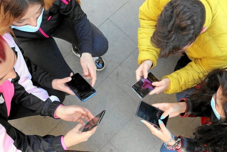 Gazte talde bat, denek eskuetan mugikorra dutela.