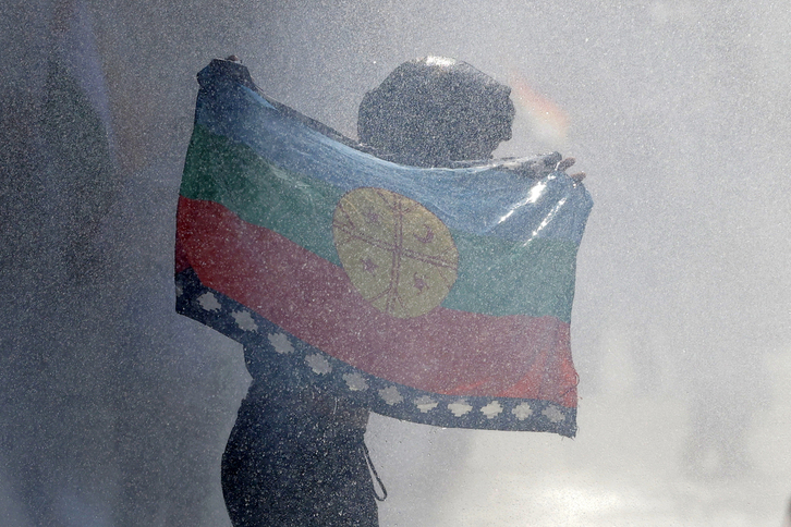 Imagen de archivo de un manifestante con una bandera mapuche escapando de la Policía durante una marcha por la resistencia mapuche y de todos los pueblos indígenas en Santiago.