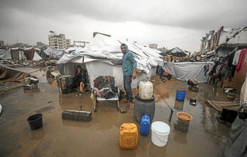Palestinos tratan de secar los enseres de las tiendas anegadas.