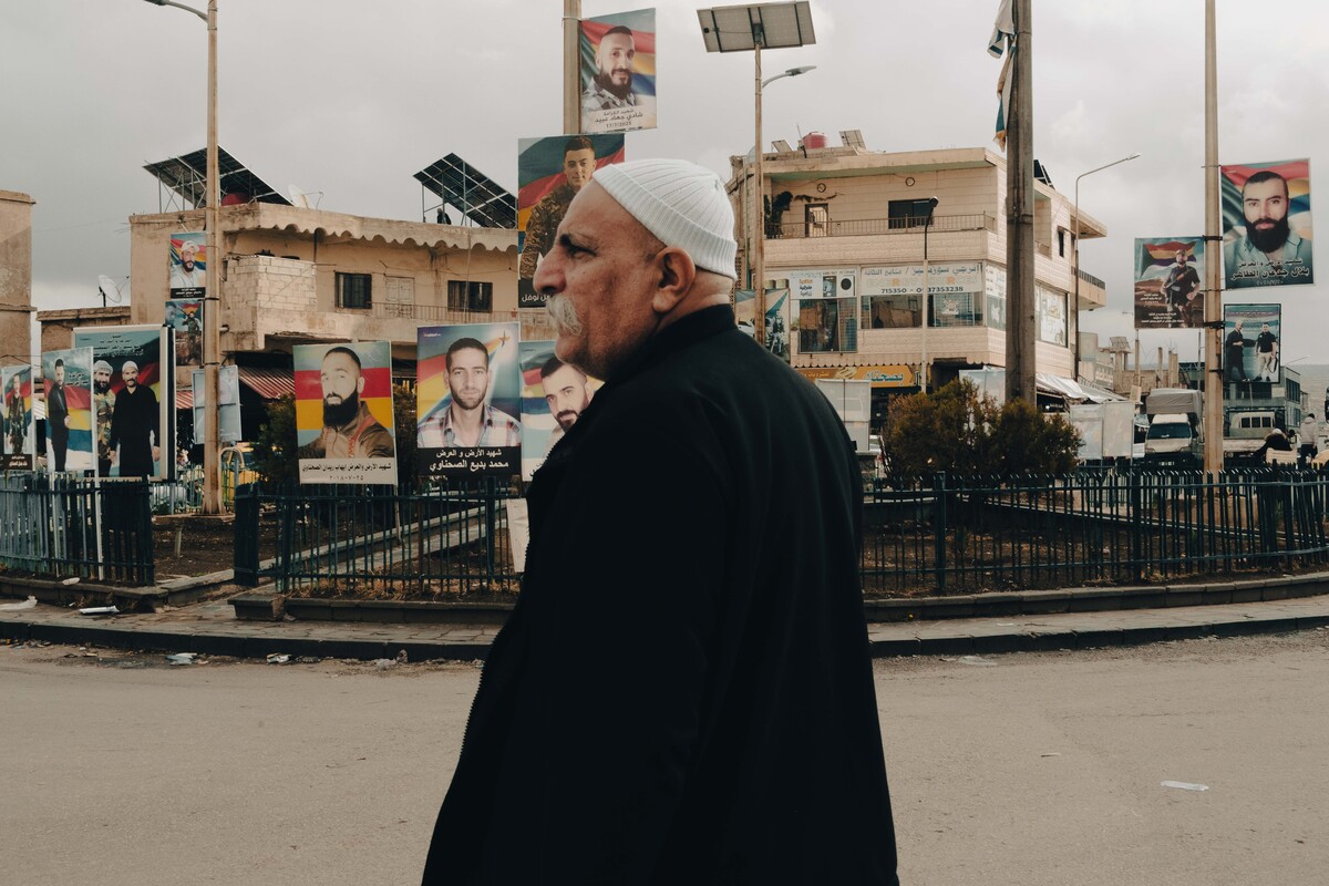 Un hombre druso en el pueblo de Shahba. Detrás de él, retratos de combatientes drusos muertos este verano en los enfrentamientos. (Laurent PERPIGNA IBAN)