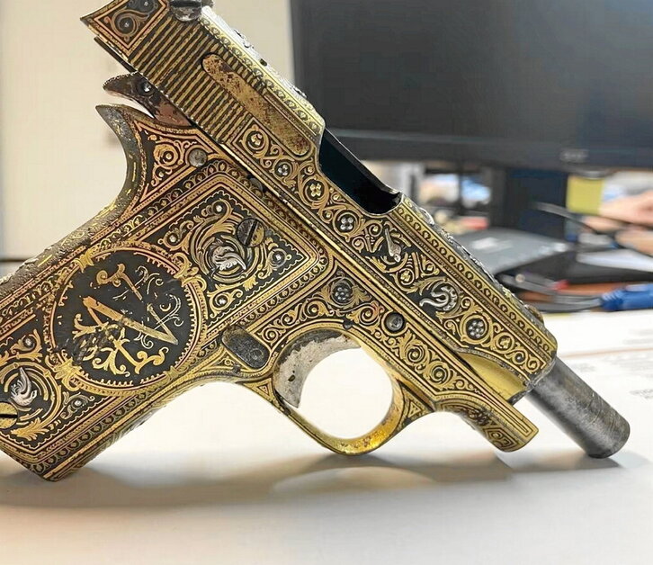 La pistola tiene detalles de oro y plata.