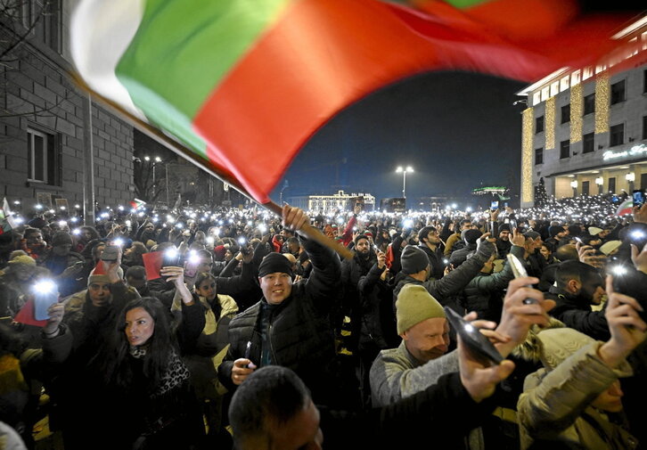 Manifestari bat, Gobernuaren aurkako protesta batean Bulgariako bandera astintzen, abenduaren 10ean, Sofian. Hurrengo egunean Gobernuak dimisioa eman zuen.