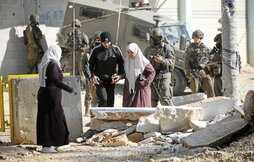 Palestinos abandonan sus hogares en el campo de Nour Shams vigilados por soldados israelíes.