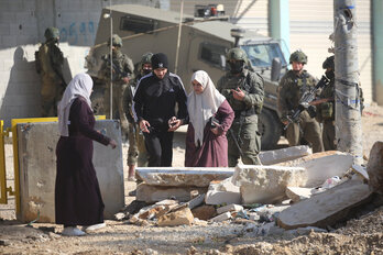 Palestinos abandonan sus hogares en el campo de Nour Shams vigilados por soldados israelíes.