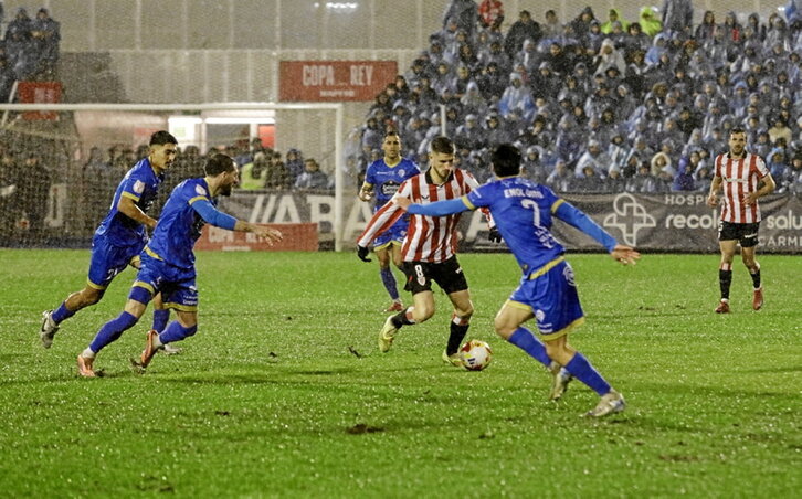 Oihan Sancet intenta conducir el balón rodeado de rivales del Ourense en una noche muy lluviosa.