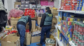 Guardias civiles inspeccionan un local de venta de juguetes.