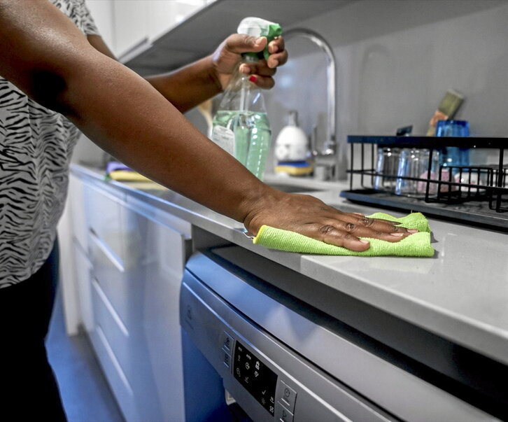 Una mujer limpia la encimera de la cocina.