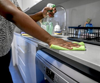 Una mujer limpia la encimera de la cocina.