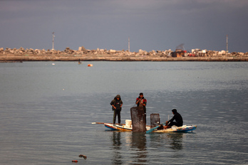 Pescadores reman en un bote improvisado con una jaula utilizada para atrapar cangrejos en el principal puerto pesquero de la ciudad de Gaza, el 10 de diciembre.
