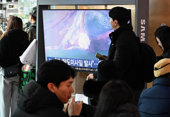 Gente frente a una pantalla de televisión que muestra imágenes de archivo de una prueba de un misil norcoreano, en una estación de tren de Seúl, este domingo.