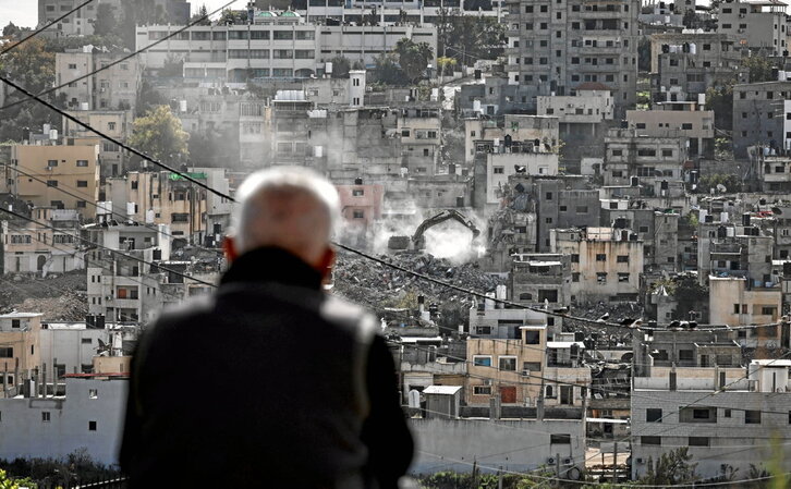 Residentes del campo de refugiados de Nur Shams observan cómo una excavadora militar israelí derriba sus casas.