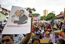 Un manifestante sostiene un cartel en Caracascon la imagen de Maduro y Flores.