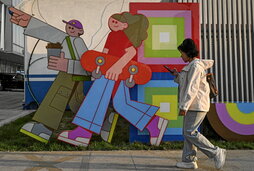 Emakume gazte bat, mugikorra eskuan, Pekingo kale batean.