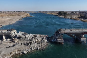  Un grupo de personas intenta cruzar las ruinas de un puente destruido a orillas del Éufrates en la ciudad de Raqqa.