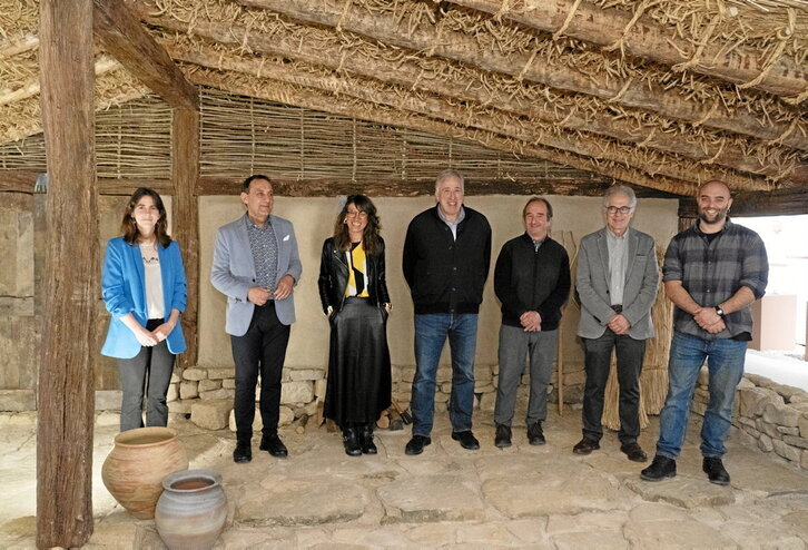 Expertos y autoridades posan ante la reproducción a escala real de la casa donde fue encontrada la Mano de Irulegi.