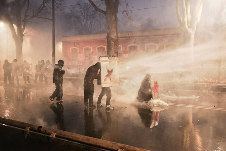 Manifestantes se protegen de los cañones de agua. 