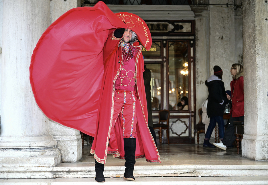 Un hombre vestido con un traje que representa los Juegos Olímpicos posa en la plaza de San Marcos.