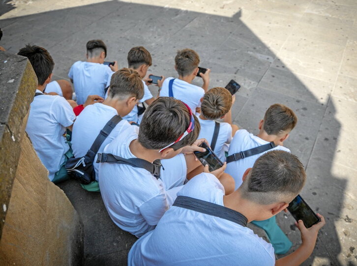 Un grupo de chavales mira atentamente sus móviles.