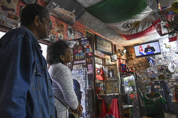 Dos ciudadanos cubanos observan la intervención televisiva del presidente del país, Miguel Díaz-Canel.