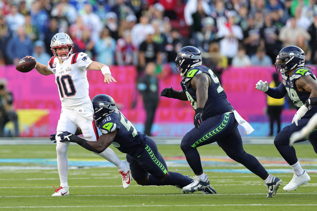 Drake Maye corre por su vida ante la presión de la defensa de Seattle.