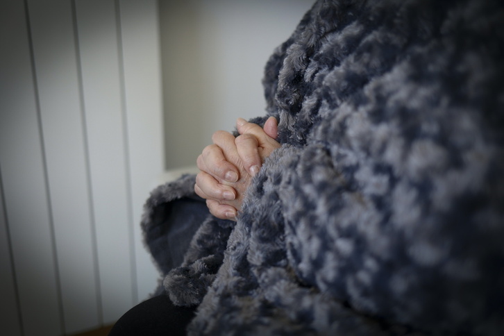Pobreza energética, una mujer trata de hacer frente al frío en casa con una manta ante un radiador que no puede encender.