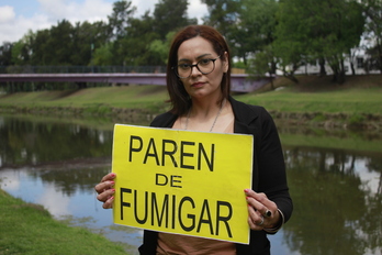 Sabrina Ortiz, víctima y querellante y referente de las comunidades en lucha, sostiene un cartel pidiendo la suspensión de las fumigaciones.