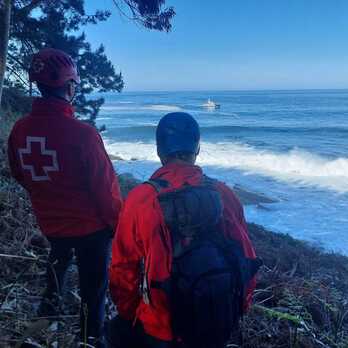 Voluntarios de Cruz Roja observan la embarcación que busca al desaparecido en Mendexa.