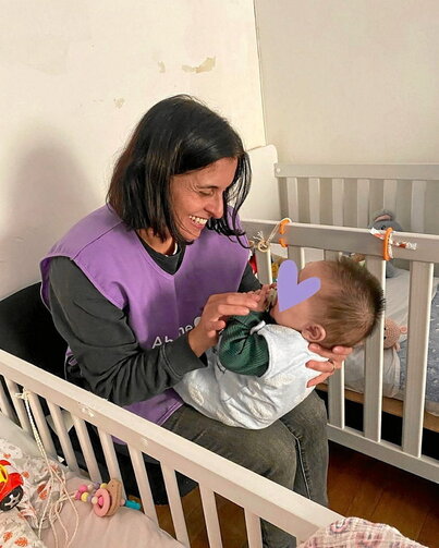 Abrázame Fundazioko boluntario bat, haurtxo bati mimoak ematen.