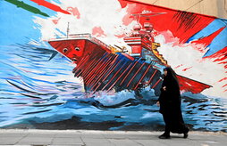 Una mujer pasa junto a un mural contra Estados Unidos en una calle de Teherán.