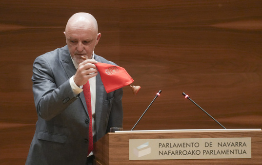 Esparza se lleva la bandera de Nafarroa que ha colocado en el estrado del Parlamento durante su defensa de la supresión de la Transitoria Cuarta..