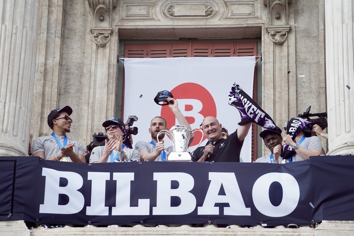 Hlinason y Ponsarnau sostienen en el balcón del consistorio bilbaino el trofeo de la FIBA Europe Cup revalidada por los hombres de negro.